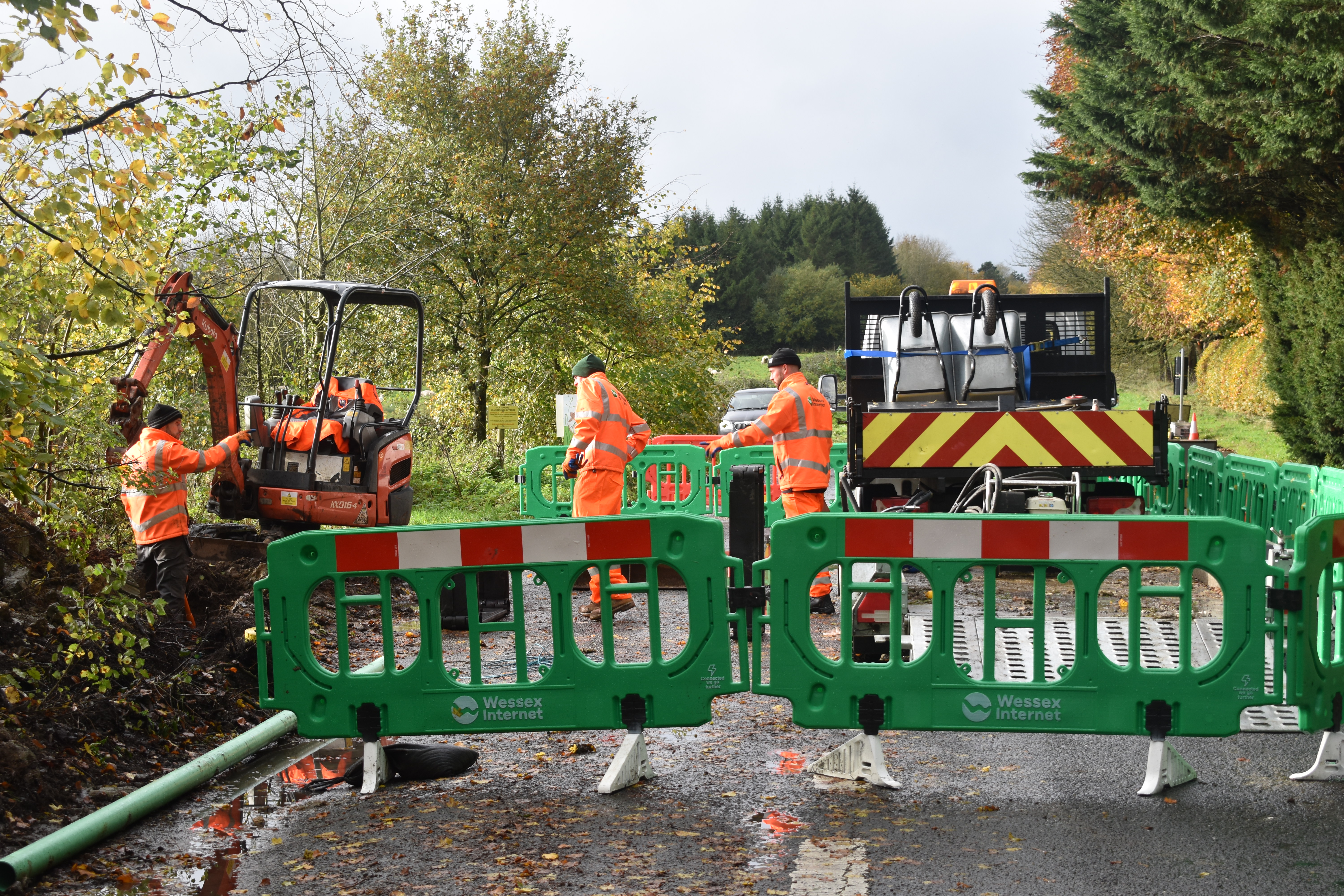 Male workers in high vis clothing and Wessex Internet branded barriers