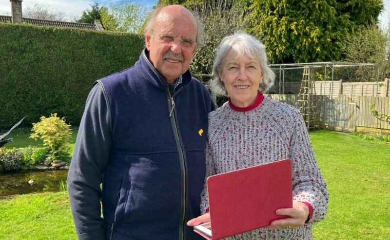 Lawrence and Pam Hopkins in the garden holding a laptop.