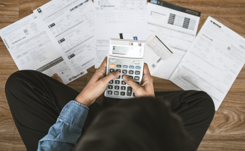 Person sat down with bills and a calculator 