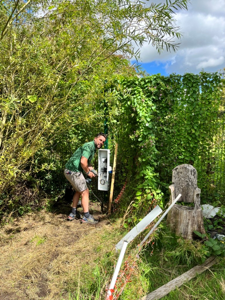 Employee installing a wildlife camera to a fence