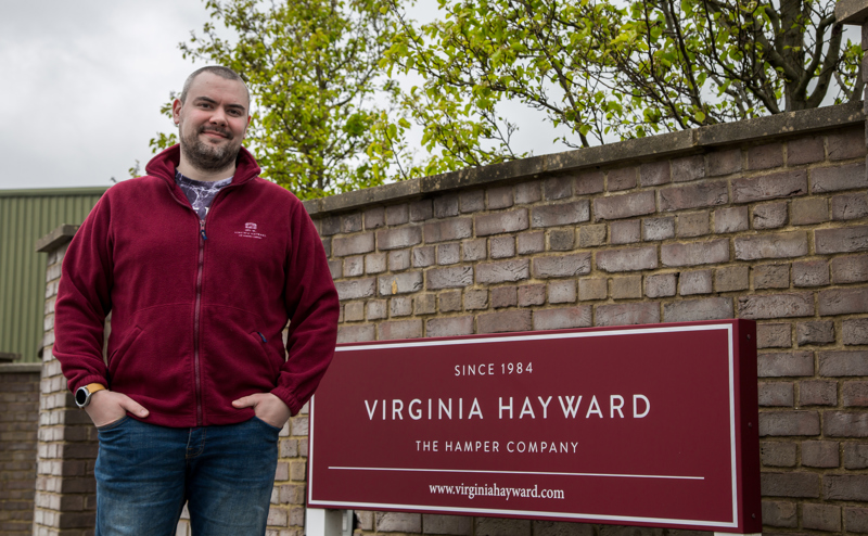 Employee stands next to Virginia Hayward Hamper company sign in Dorset.