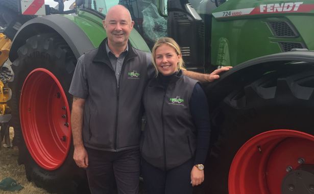A man and woman, stand in front of a Redlynch Tractor in Somerset. 