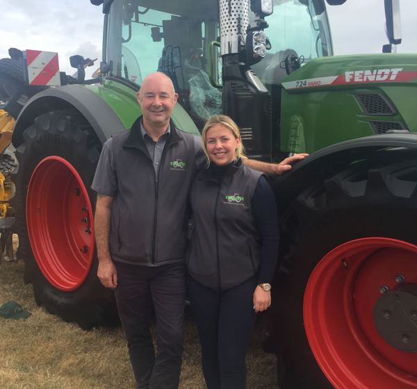 A man and woman, stand in front of a Redlynch Tractor in Somerset. 