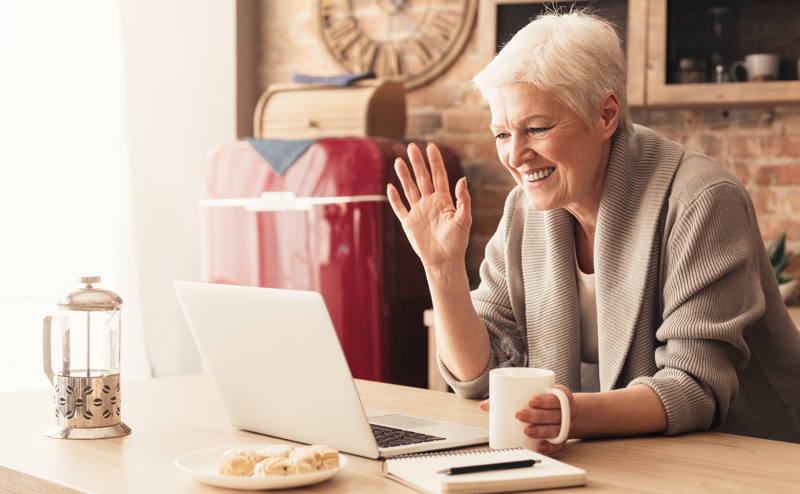 Mature lady sat at a laptop with hot drink