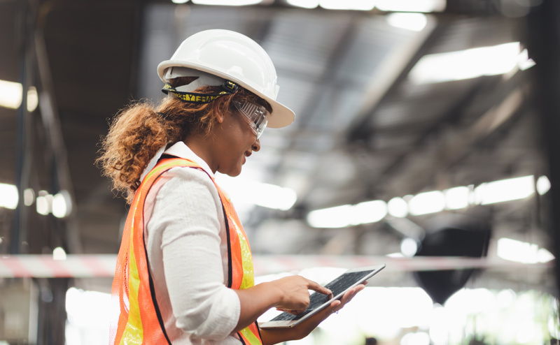 Female on an iPad with hard hat and protective goggles