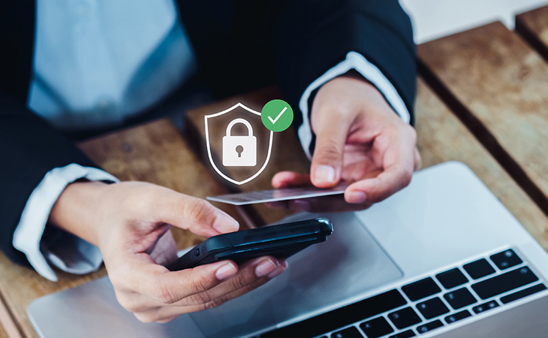 Person sat at a laptop with a mobile and credit card